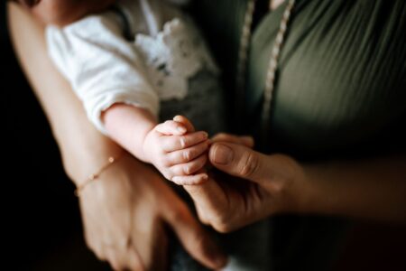 Close-up of a mother holding her baby's hand, capturing a tender and intimate moment.